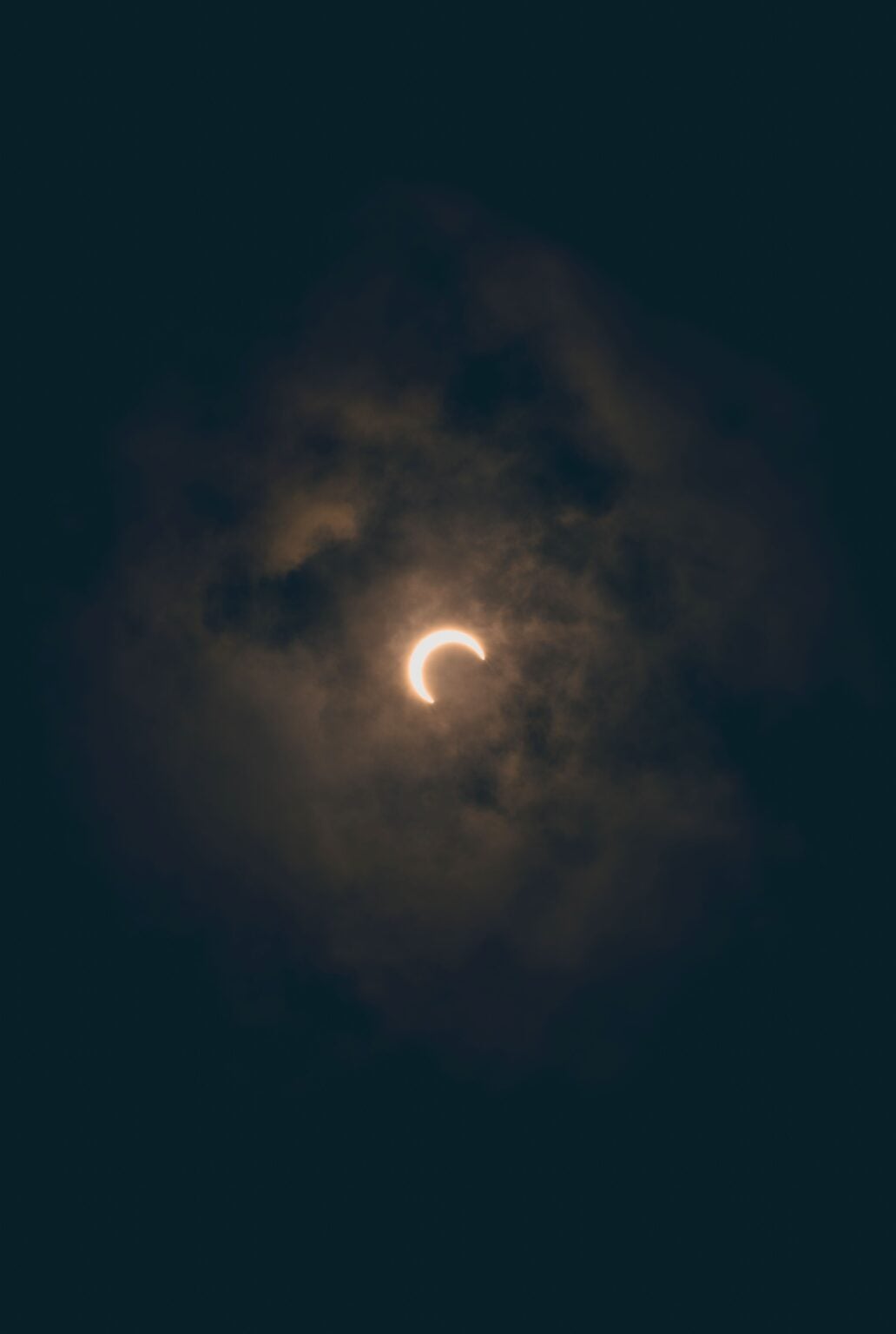 A moody lunar eclipse surrounded by dense clouds in Akumal, Mexico's night sky.