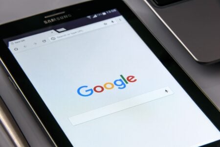 AI Overviews : comment Google a bouffé jusqu’à 61 % du trafic des sites Close-up of a tablet displaying Google's search screen, emphasizing technology and internet browsing.