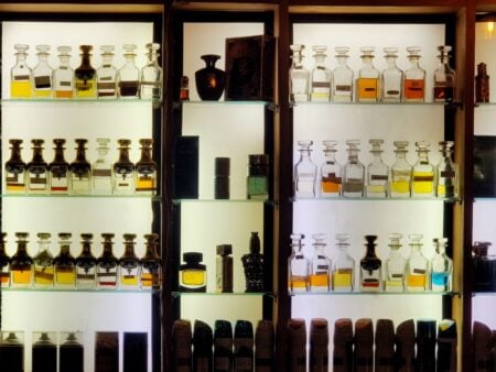 Parfum de niche : pourquoi il est devenu un sujet de conversation à part entière Aesthetic arrangement of diverse perfume bottles on illuminated shelves showcasing luxury fragrances.