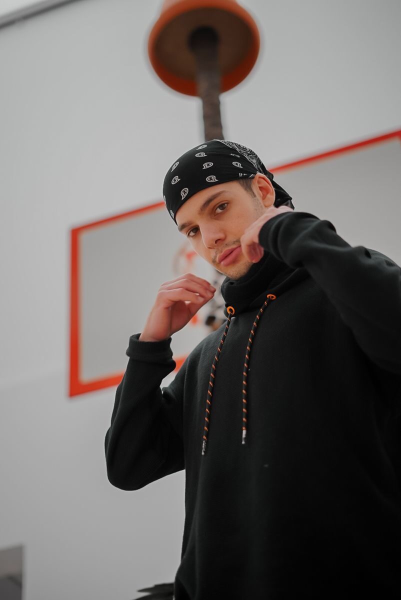 Portrait of a young man in a black hoodie and bandana indoors.