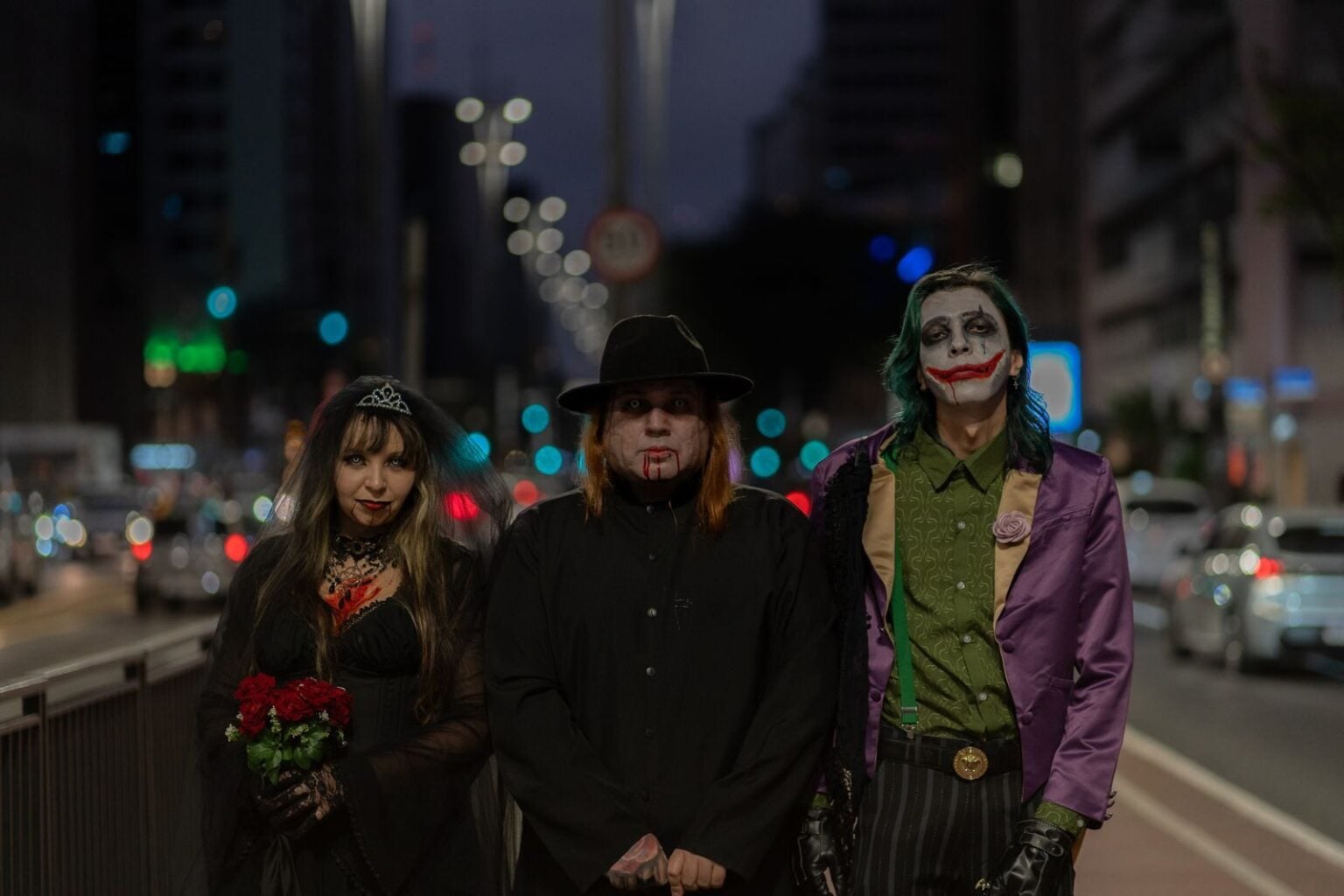 Halloween 2026 : les déguisements cinéma qui vont cartonner, et comment éviter le costume sous cellophane A trio in Halloween-themed cosplay walking through a bustling city street at night.