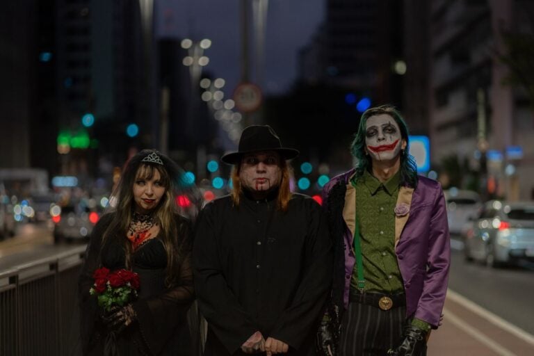 A trio in Halloween-themed cosplay walking through a bustling city street at night.