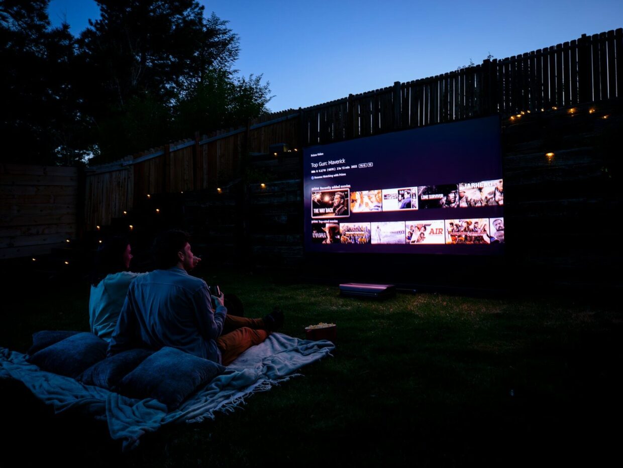 Two people sitting on a blanket watching a movie