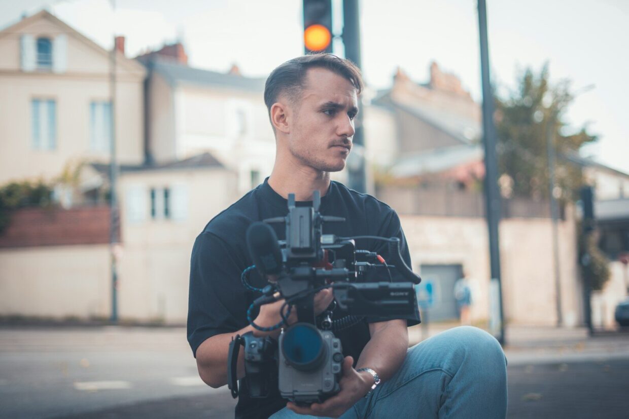 Man holding a professional video camera outdoors