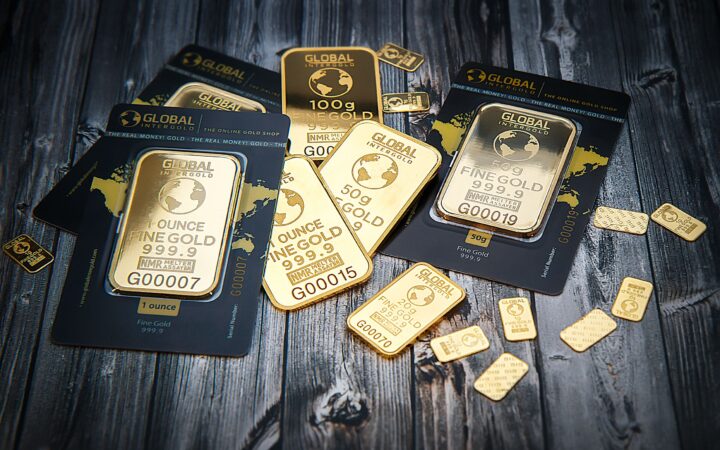 A collection of fine gold bars displayed on a textured wooden surface.